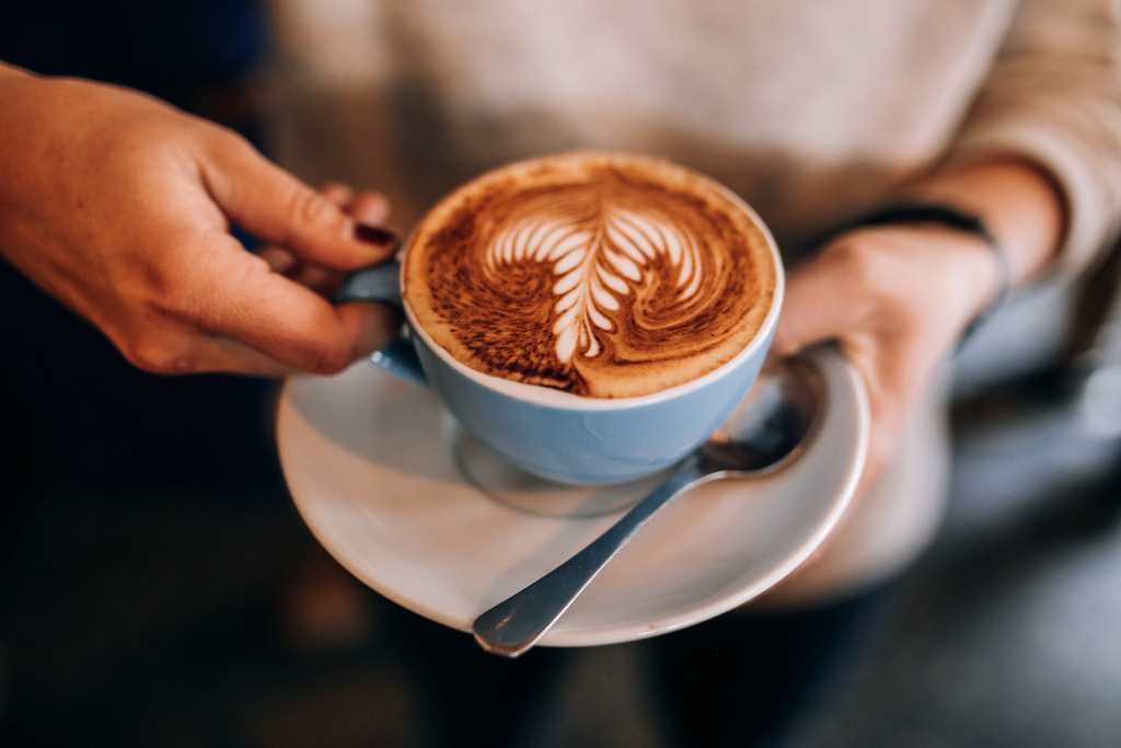 woman-holds-cup-saucer-with-hot-latte-coffee.jpg